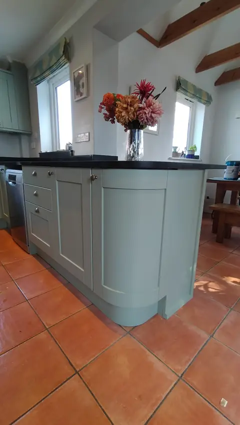 Sage green curved island on terracotta tiles