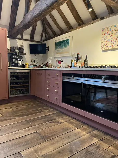 Dusky pink units in a beamed country kitchen